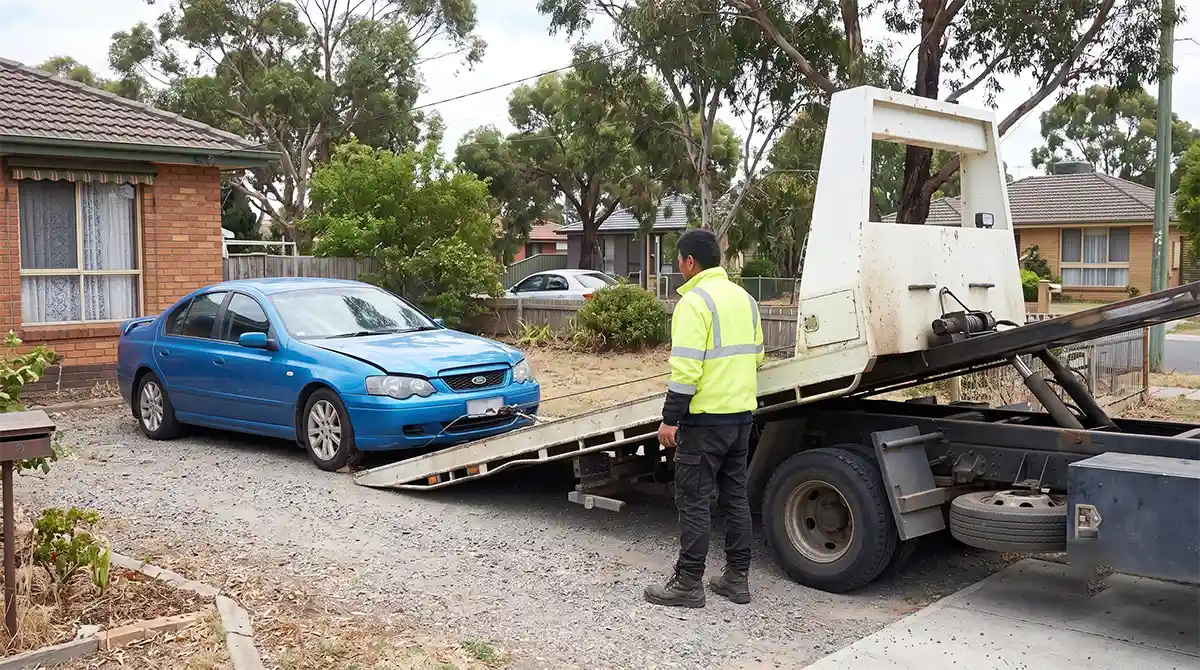 Amiry Cash For Cars driver loading an unwanted sedan onto a flatbed tow truck in a residential driveway in Tarneit